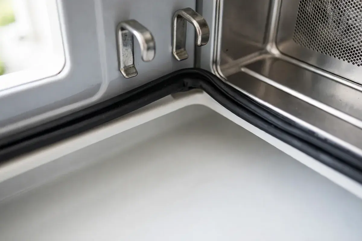 Open microwave door area showing the latch hooks and seal edge